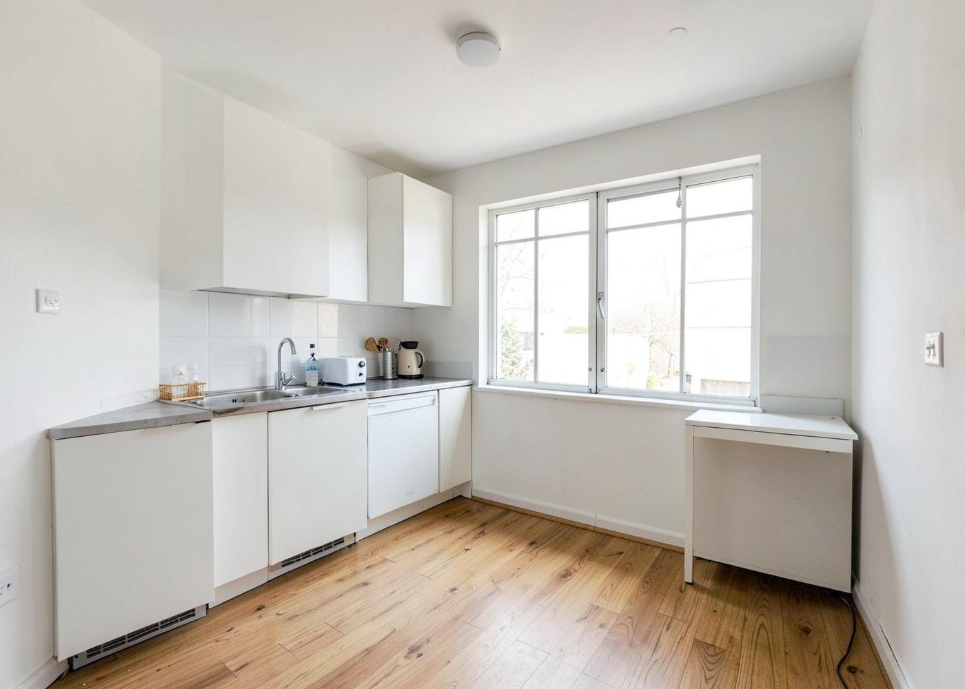 Interior of a converted garage studio with kitchenette and oak flooring